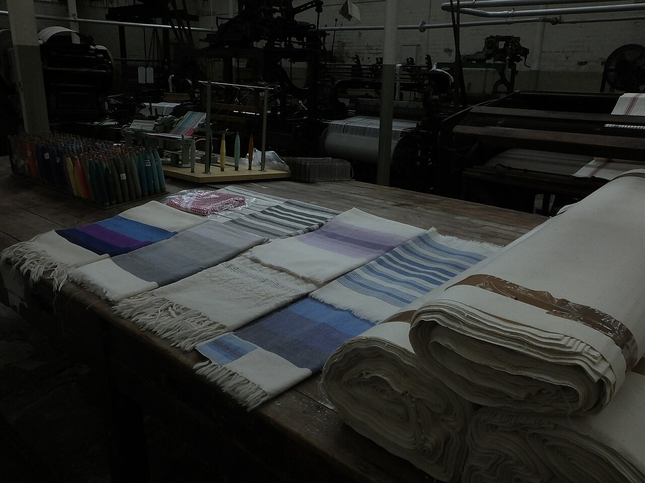 Cloth woven at Queen Street Mill, Burnley, laid out beside the looms